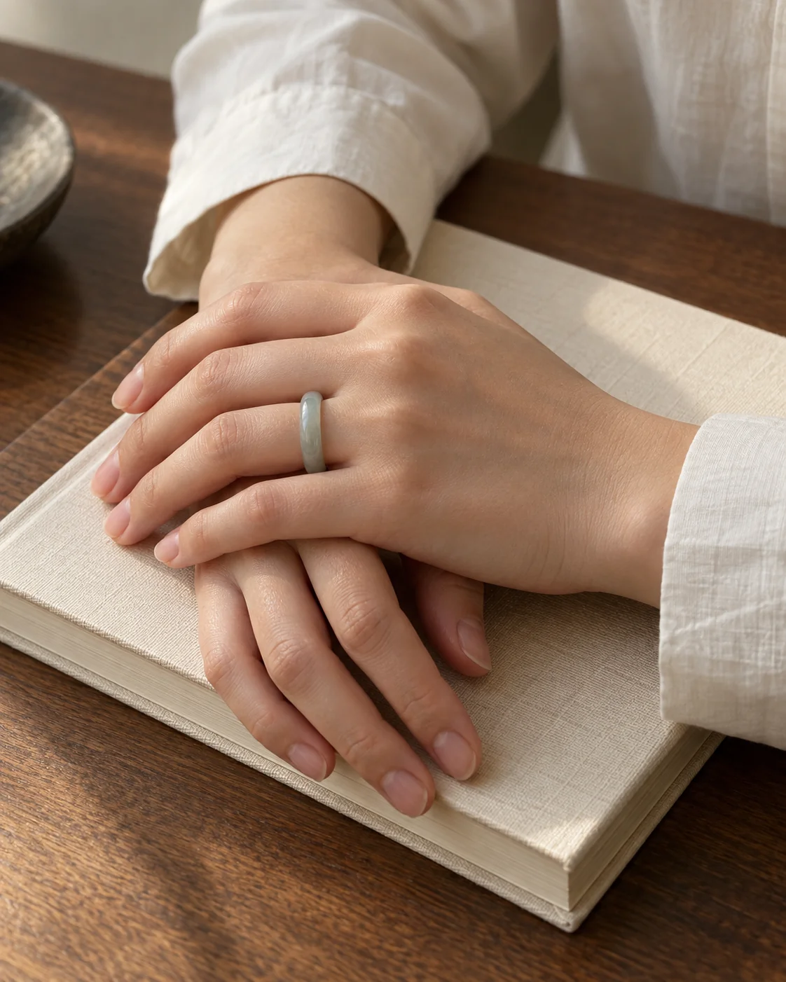 A slim jade band worn while resting hands on a book